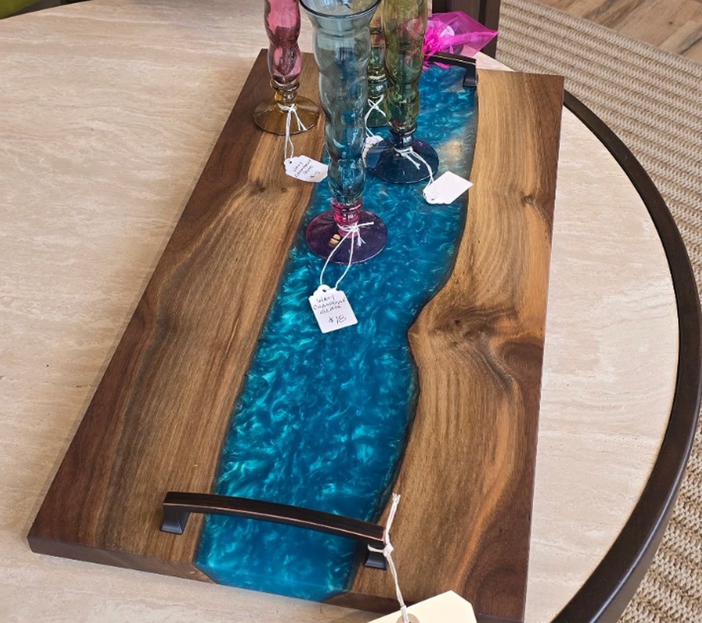 Live-edge walnut charcuterie board with an aqua resin river and a forged handle.