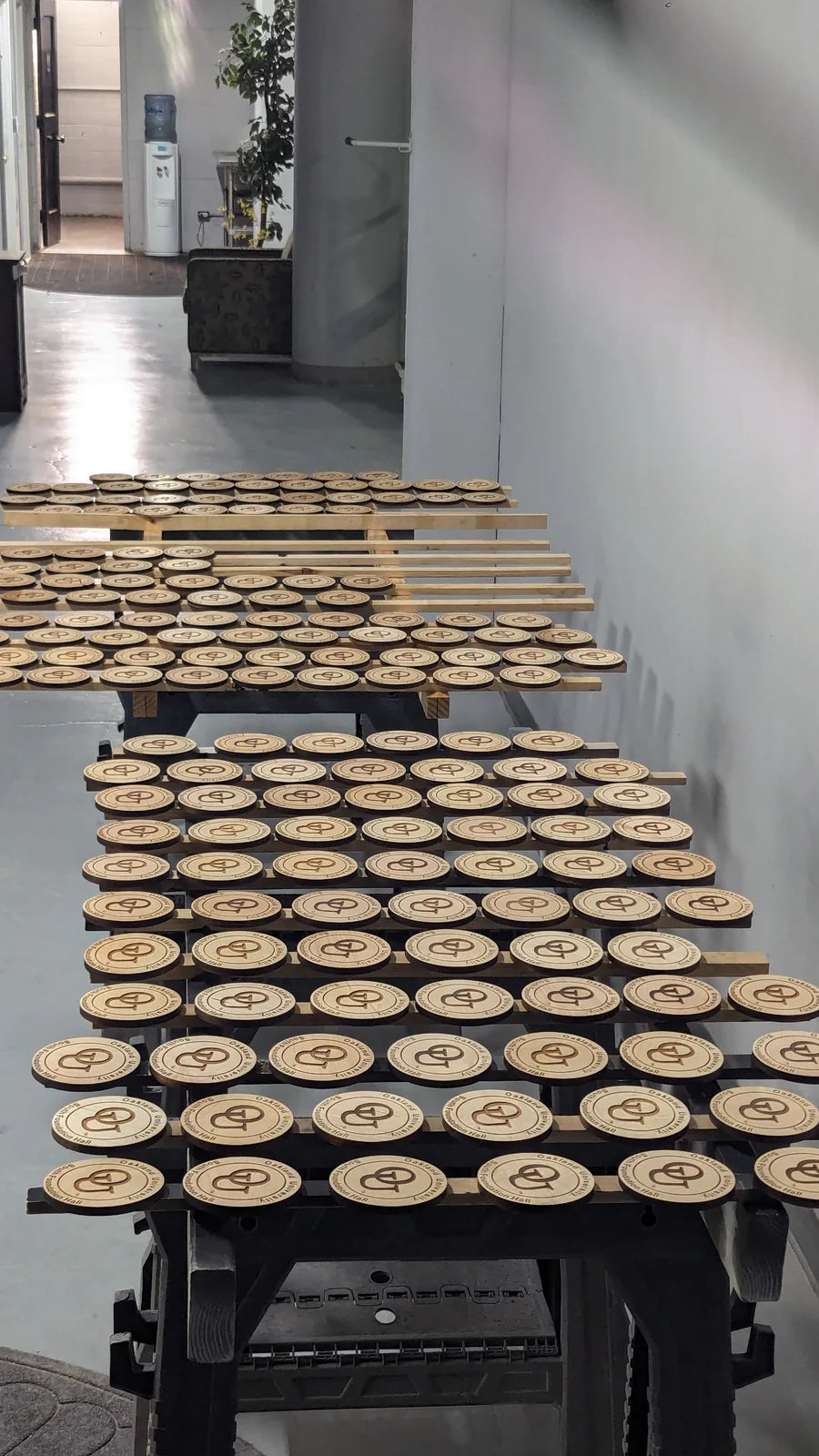 Hundreds of engraved coasters laid out across benches to finish.