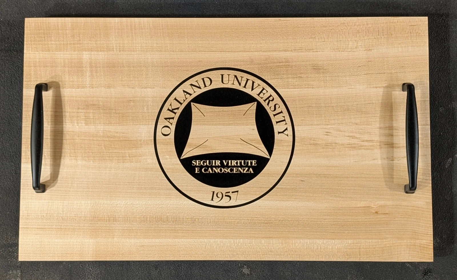 A maple serving tray with black iron handles, engraved with the Oakland University seal.