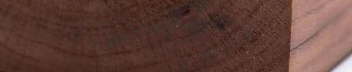 Close grain of a planed cherry blank, warm red-brown with visible growth rings.